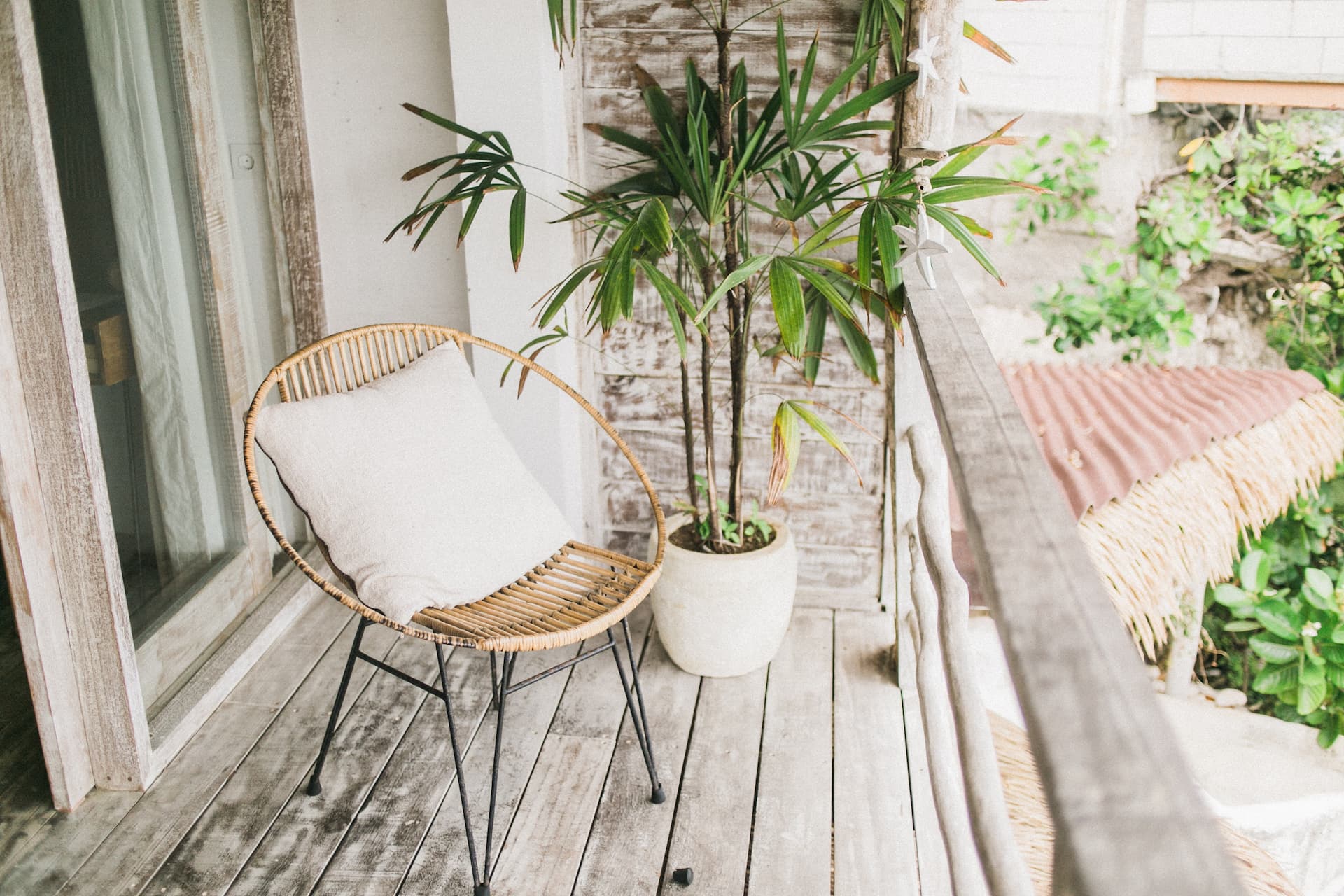 Terraza pequeña decorada con silla de mimbre y cojín